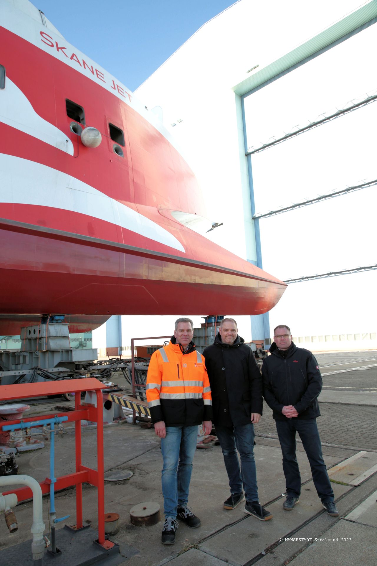 Vor dem Skane Jet und der Werfthalle, in die der Katamaran anschließend rollt v.l.n.r. Carsten Stellamanns, Geschäftsführer Fosen Yard, Oberbürgermeister Alexander Badrow und  FRS Baltic GmbH Geschäftsführer Moritz Bruns